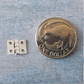 A small silver metal hinge shown next to a one dollar coin for scale, on a textured blue-gray surface.