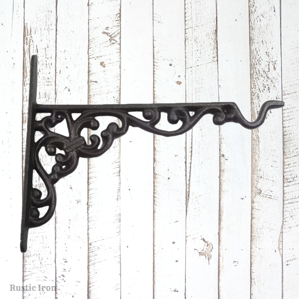 An ornate cast iron bookend bracket in a dark rustic finish, mounted on a white distressed wood plank background. 