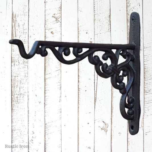 A black wrought iron decorative wall bracket with ornate scrollwork, mounted 