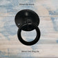 Black forged iron ring pull with a 38mm diameter ring and a 50mm diameter dome, rustic design on a light wood background.