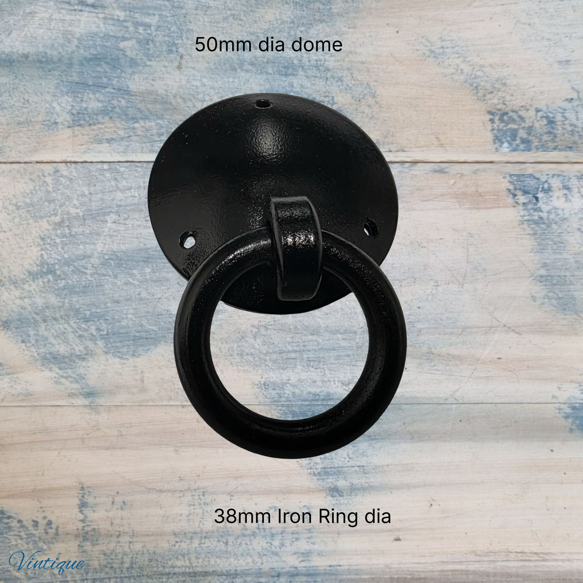 Black forged iron ring pull with a 38mm diameter ring and a 50mm diameter dome, rustic design on a light wood background.