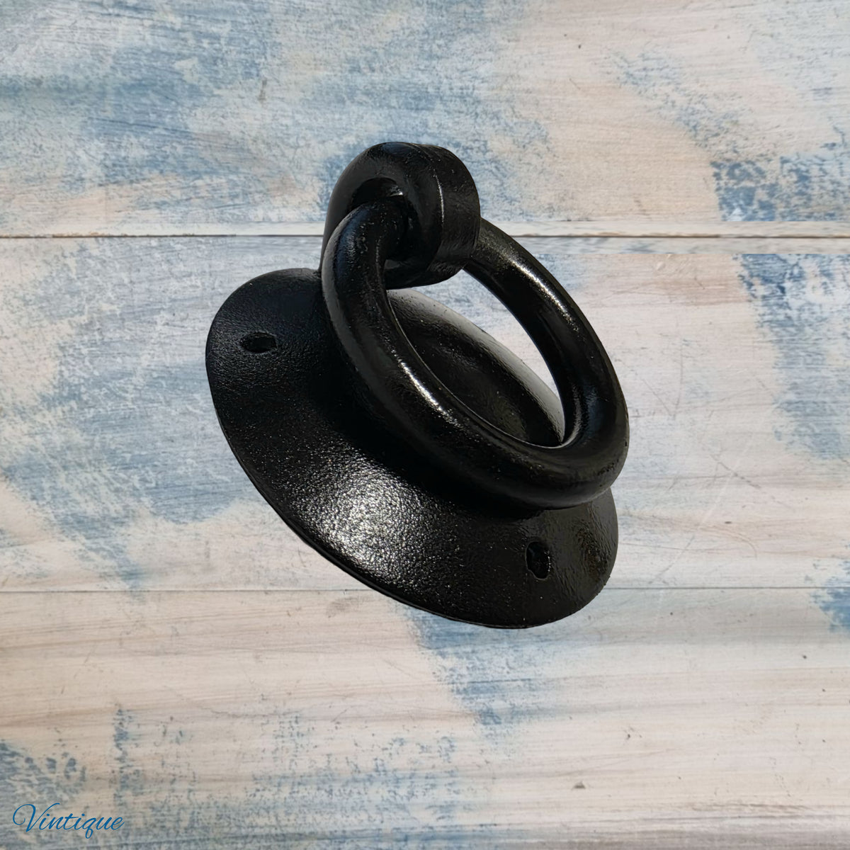 Black forged iron ring pull with a circular base, featuring a rustic design and a smooth finish.