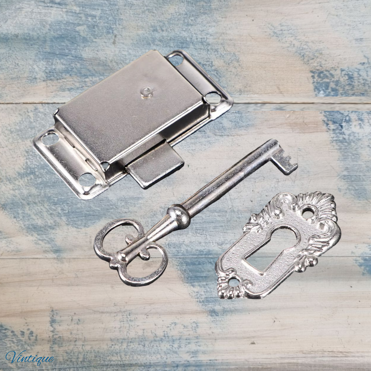 Antique silver latch lock set with key and escutcheon, featuring ornate details and a shiny finish.