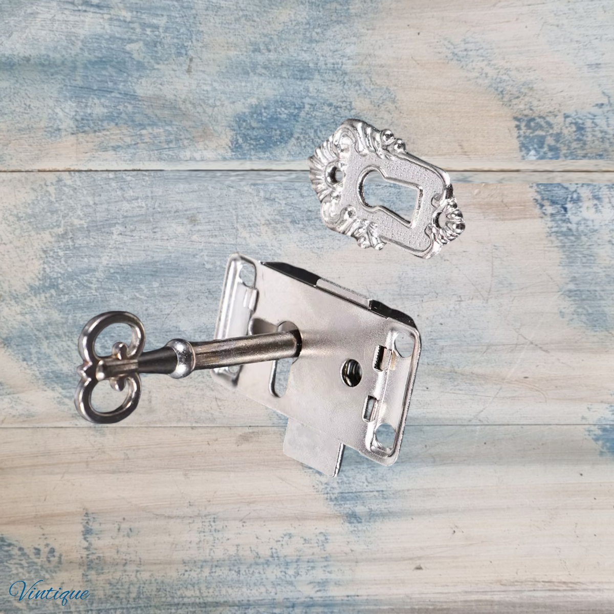Antique silver latch lock set with ornate escutcheon and key, featuring intricate detailing on the escutcheon.